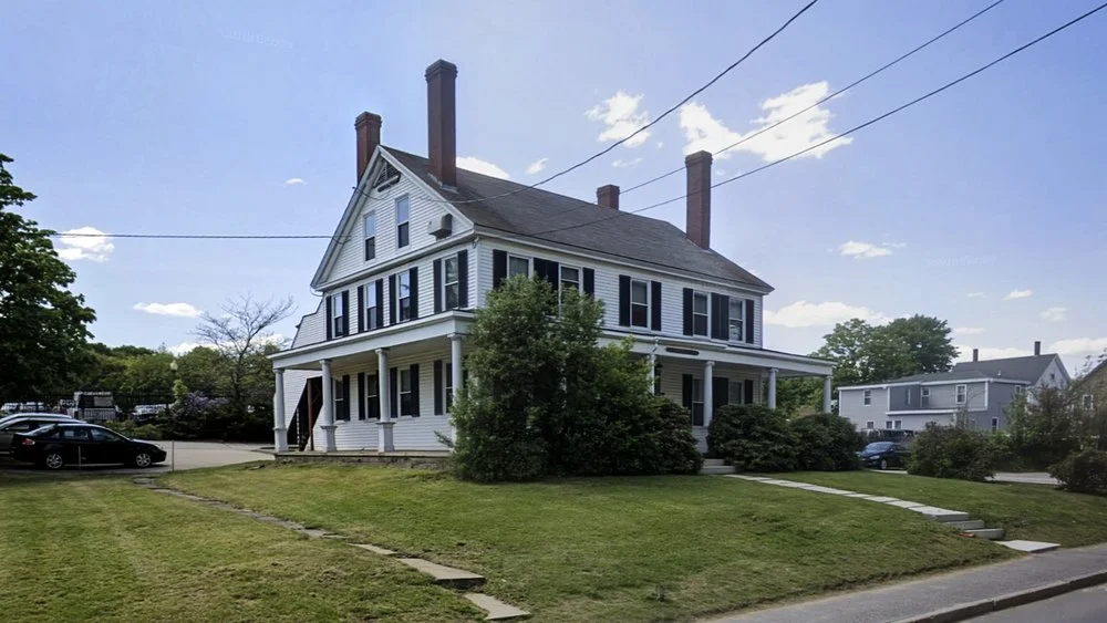 Historic white three-story home featuring brick chimneys and a covered porch.